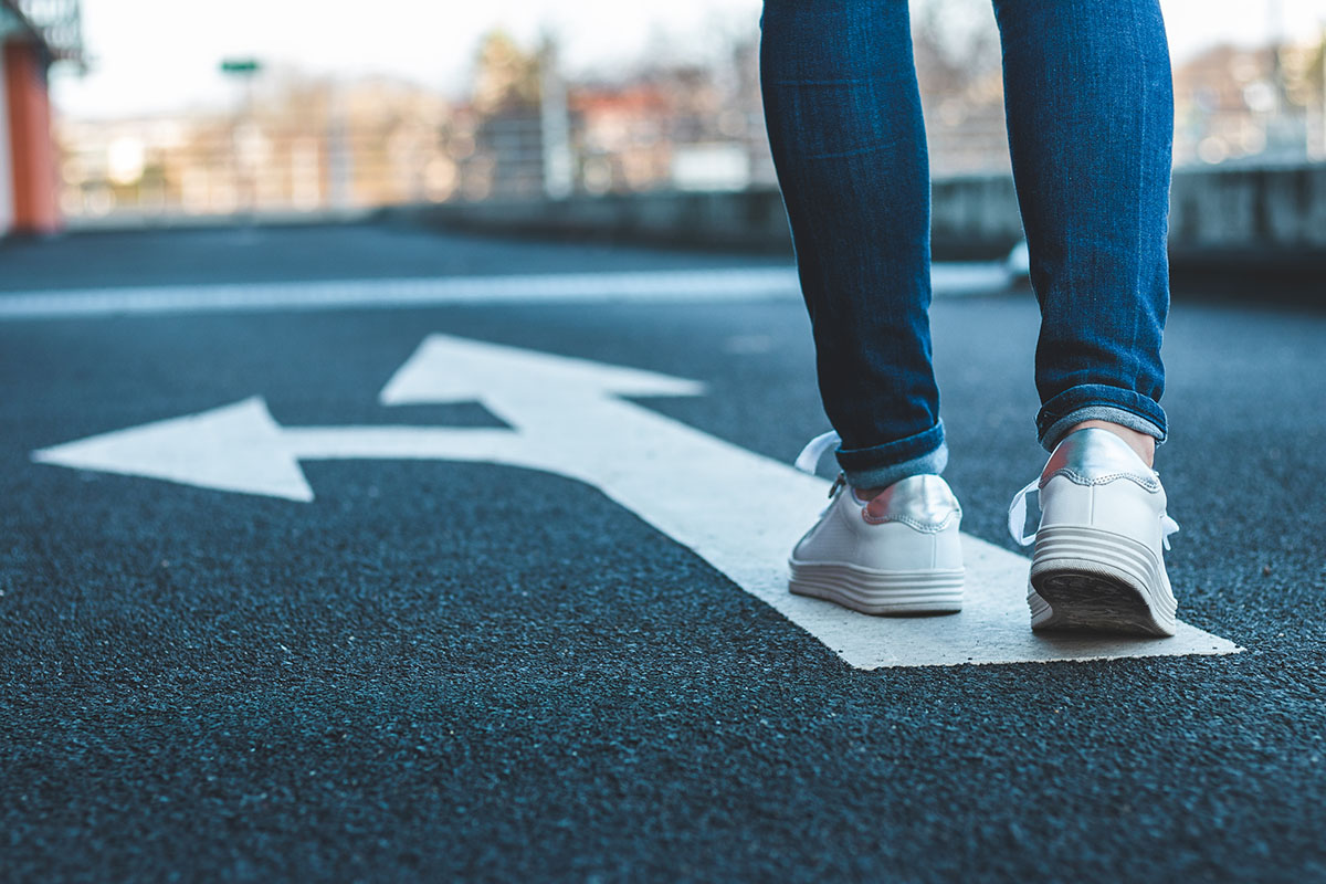 Person walking on directional sign