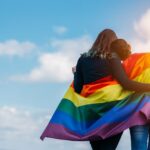 Two women hugging under rainbow flag